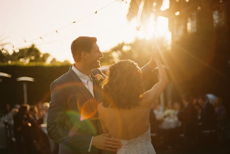 A bride and groom dancing at an outdoor reception at sunset