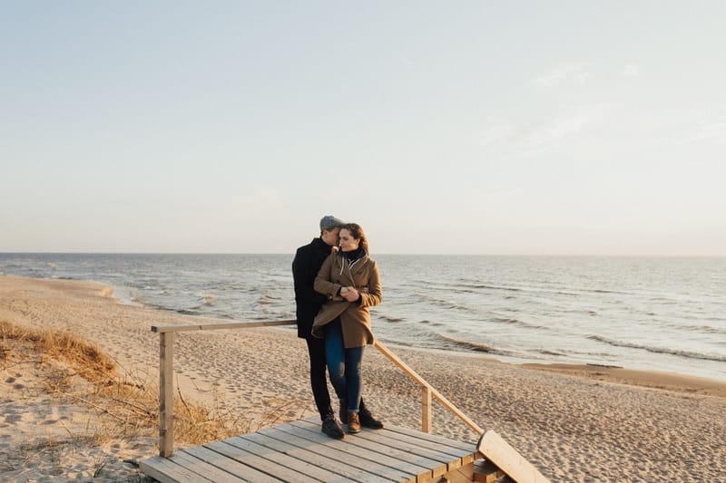 A couple embracing on a boardwalk above the sea on a grey day
