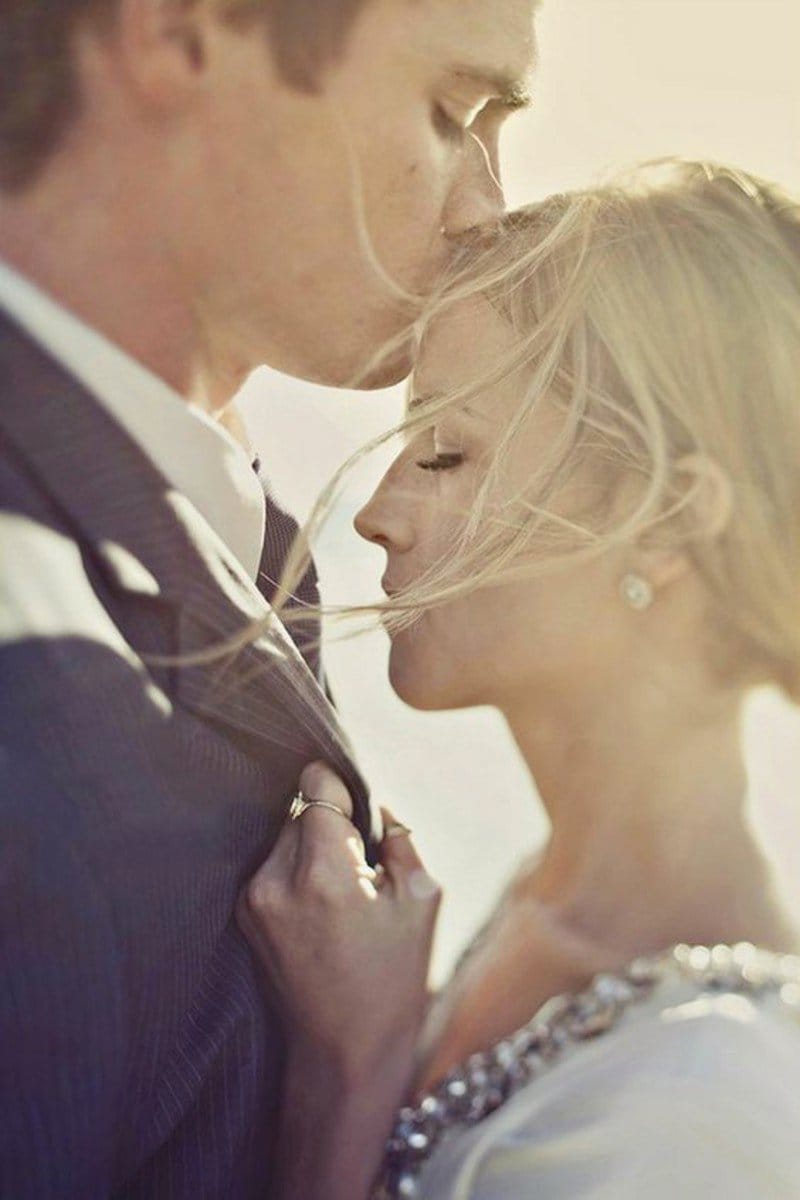Close-up of a groom kissing his bride on the forehead