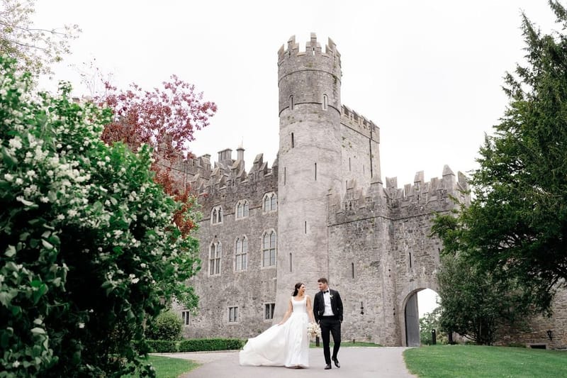 Bride and groom walking in front of Kilkea Castle in Co. Kildare