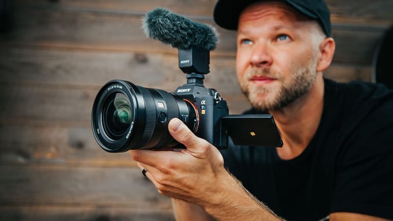 A filmmaker holding a modern mirrorless camera with an on-camera microphone